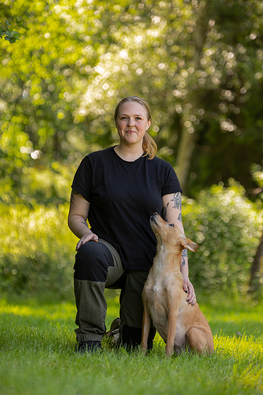 Daniella sitter i gräset med sin hund