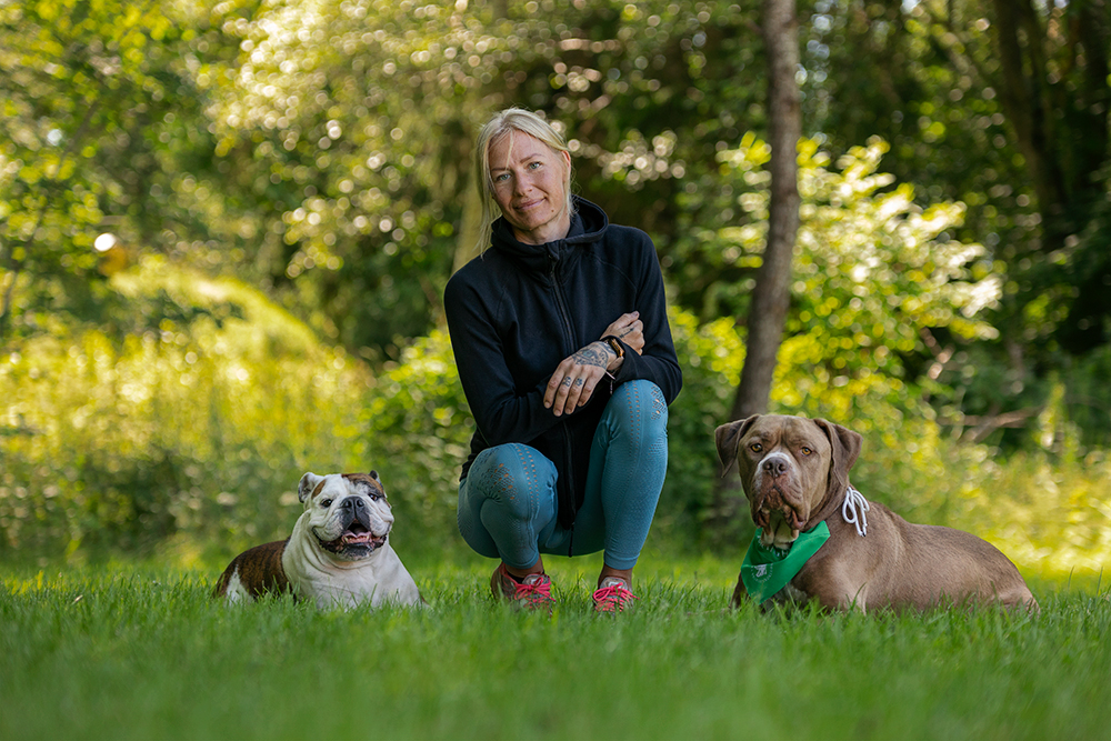 Jenni sitter i gräset med sina två hundar